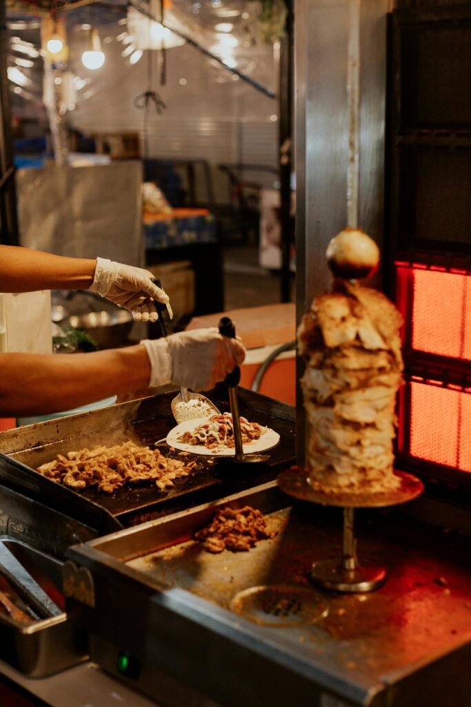 Chef prepares doner kebab with fresh ingredients at a food stall.